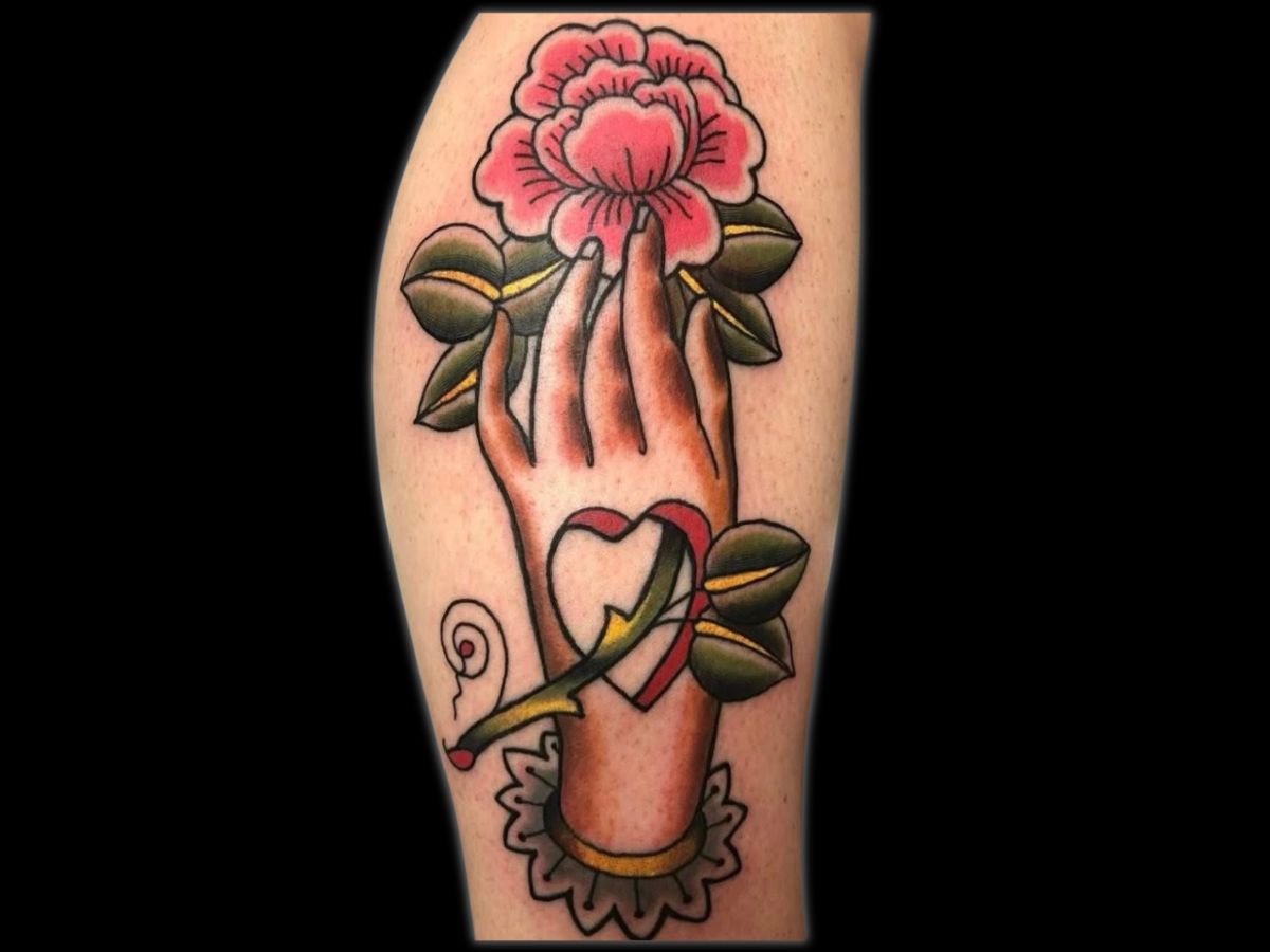Hand holding a heart and rose tattoo by Robert — neotraditional shading and detail.