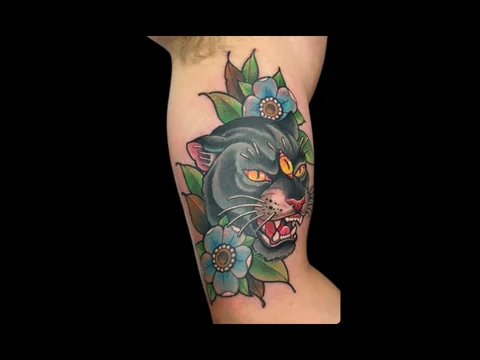 Traditional black panther tattoo with blue flowers by Robert at Earth’s Edge Tattoo & Piercing in Winston-Salem, NC